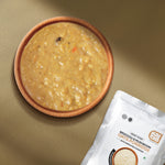 A bowl filled with oatmeal-style broccoli and mushroom porridge  with sprouted cashews along with the product. 