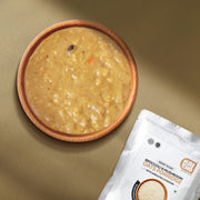 A bowl filled with oatmeal-style broccoli and mushroom porridge  with sprouted cashews along with the product. 